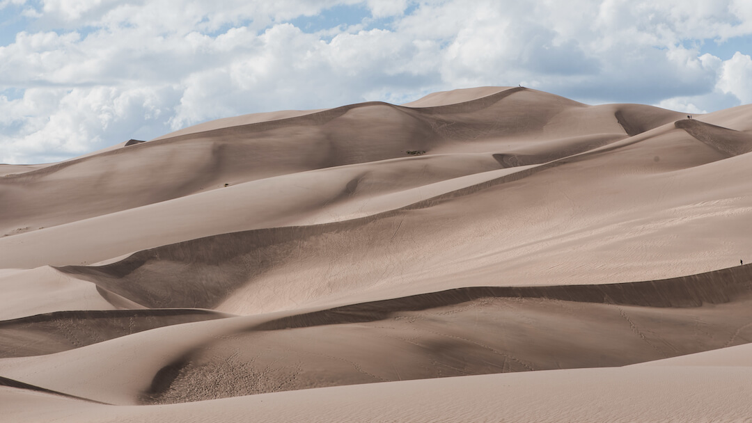 Foto de unas dunas con un cielo con nubes blancas espesas