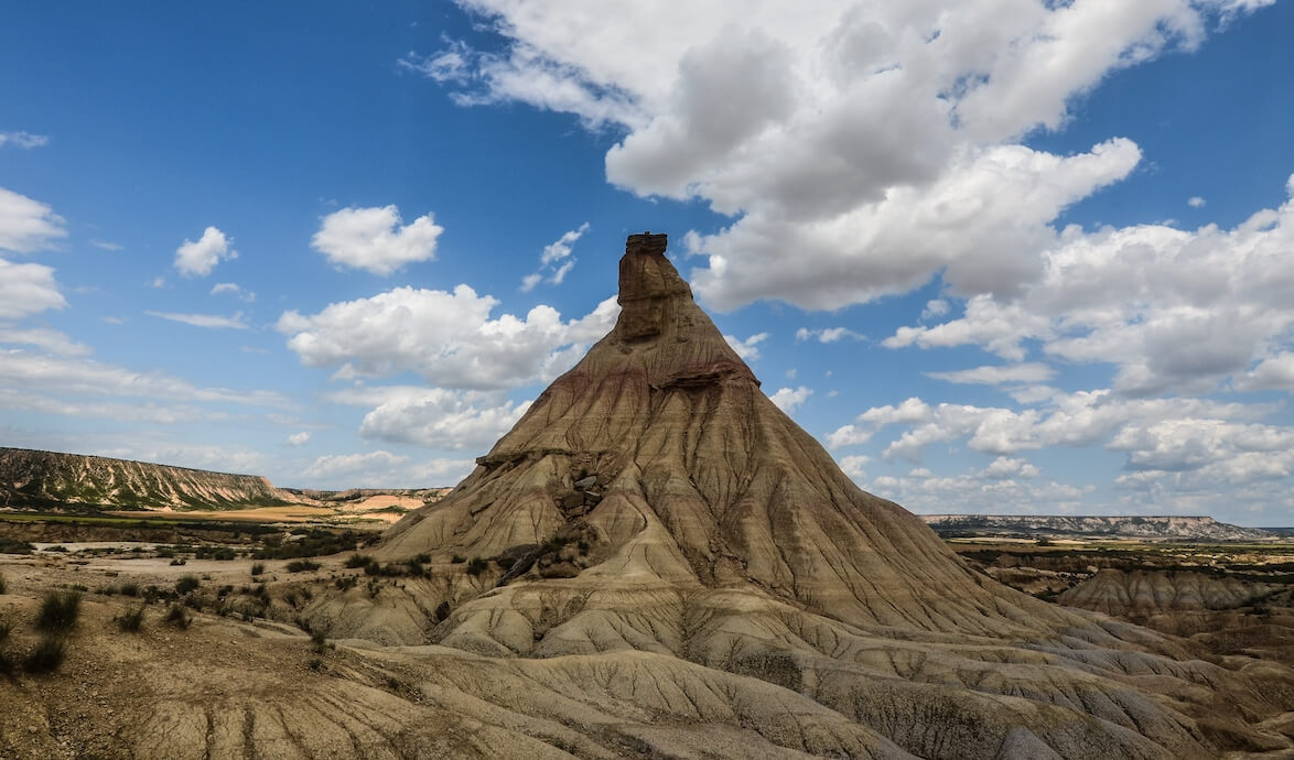 formación rocosa con forma de cono, en un desierto de piedras, con el cielo nublado