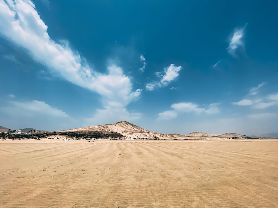 foto de un desierto de arenas claras y cielo azul intenso con algunas nubes blancas